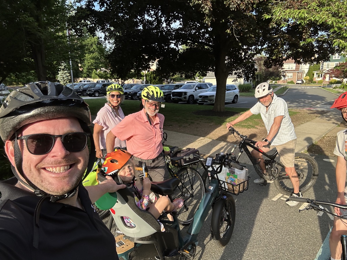 Families and neighbors gathering with bicycles and a child carrying cargo bike