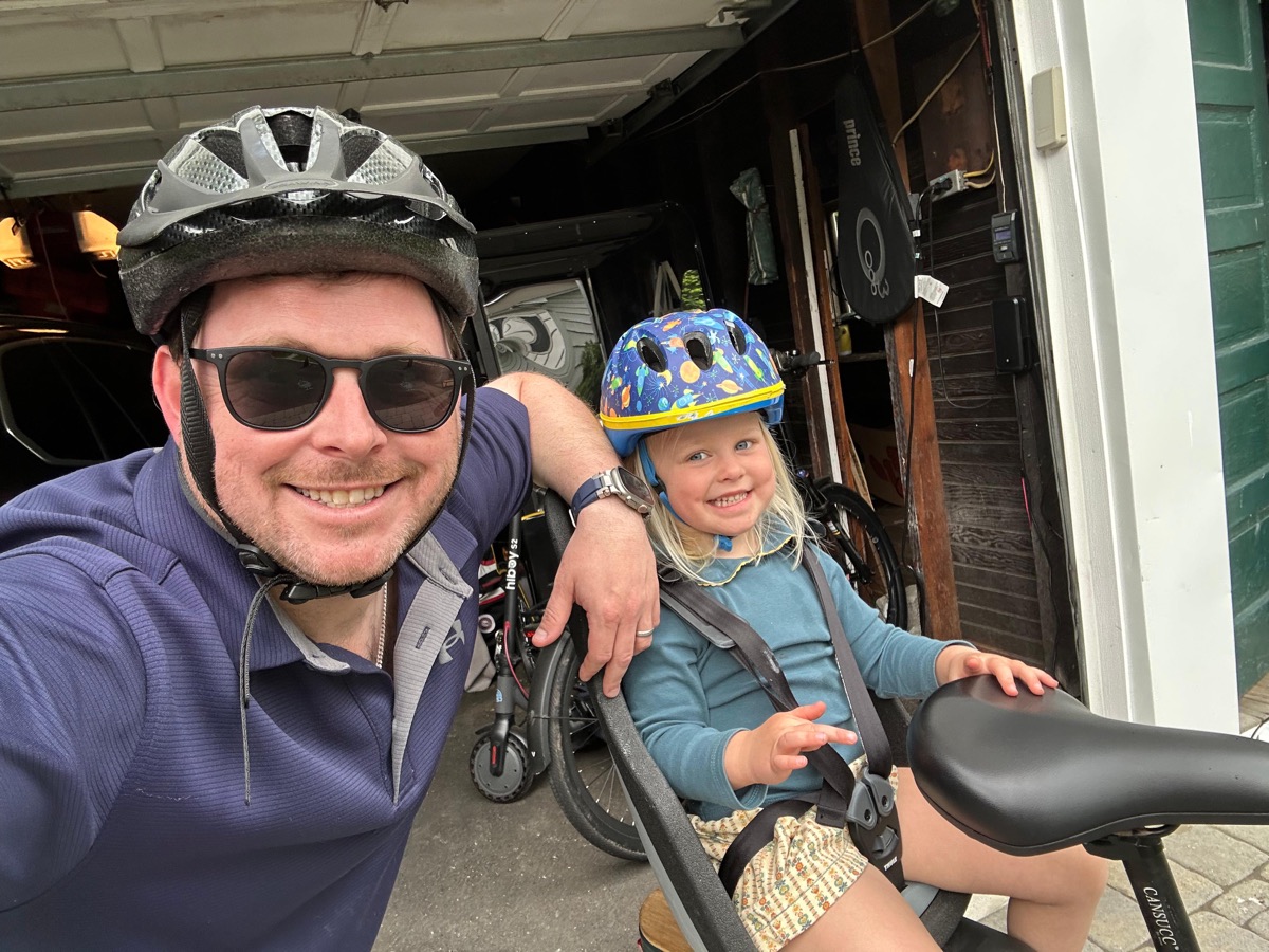 A parent and child wearing helmets and getting ready to ride